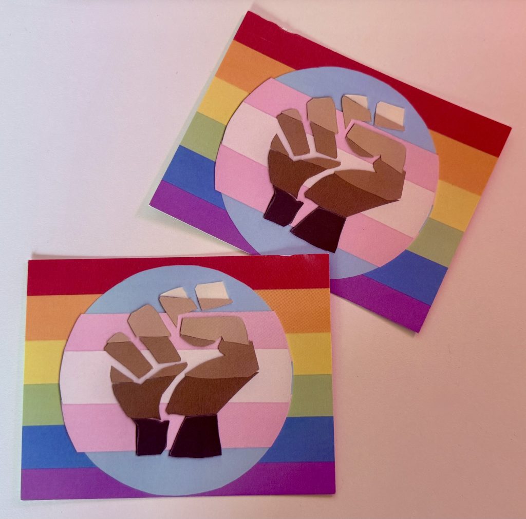 QPOC flag postcards on a white background, sent to me from a mutual! There's a slight red tinted light coming from the right side out of frame.